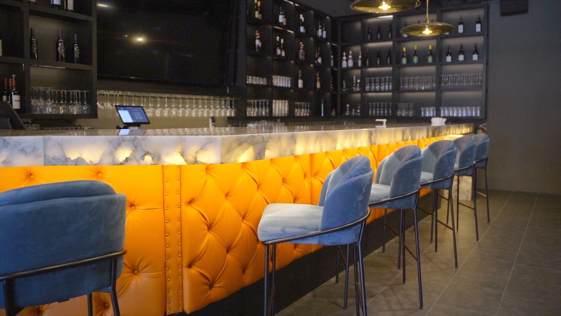 The wine bar at Dua — backlit cellar wall and marble bar